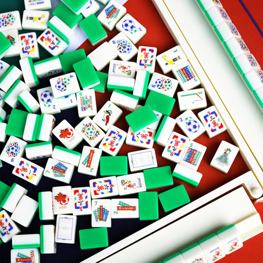 A jumbled pile of soccer themed American Mahjong tiles showing solid field-green backs mixed with referee winds and stadium flag bams.