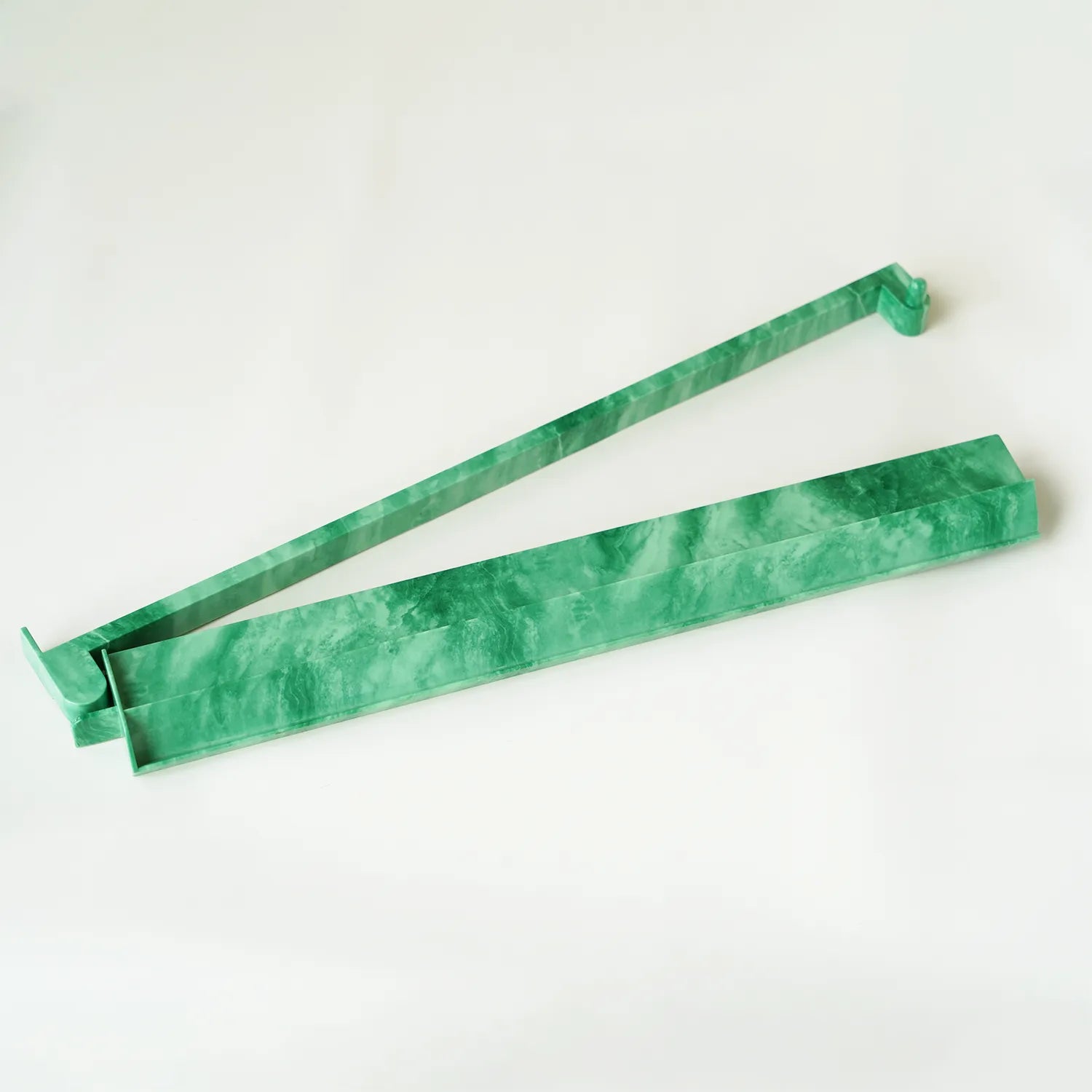 Close-up of a single jade green mahjong rack showing the built-in attached pusher extended for wall sliding.