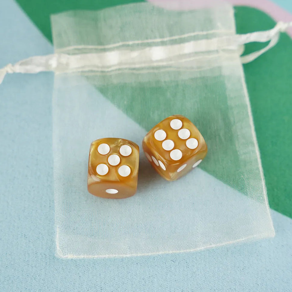 A pair of amber gold 5/8 inch marbled acrylic mahjong dice with white pips in a sheer organza pouch.