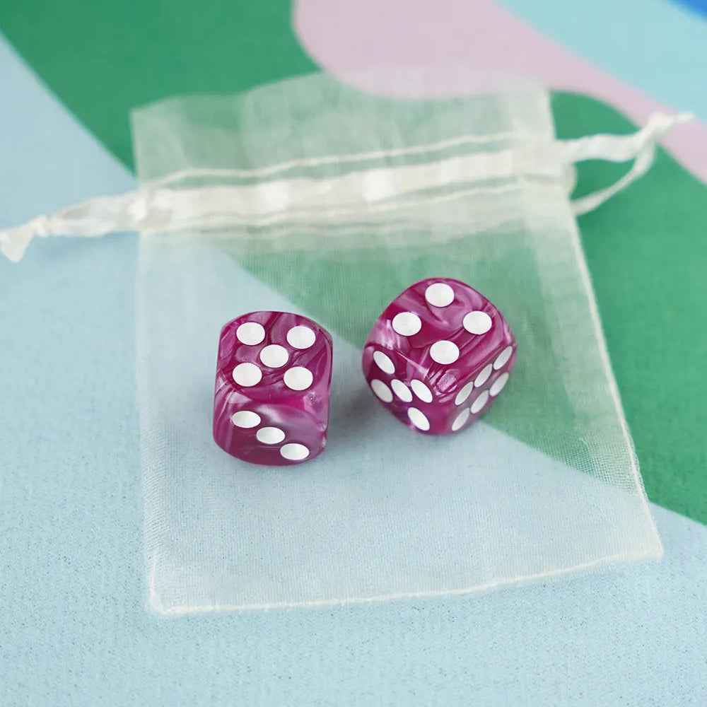 A pair of berry pink 5/8 inch marbled acrylic mahjong dice with white pips in a sheer organza pouch.