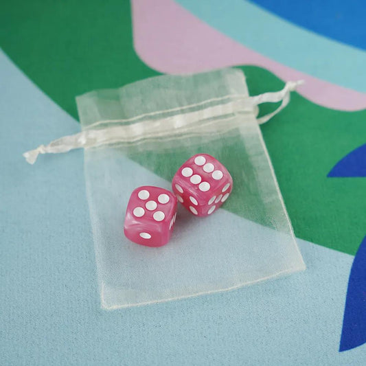 A pair of bubblegum pink marbled acrylic mahjong dice with high-contrast white pips in a sheer white organza pouch.