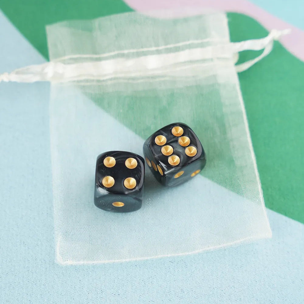 A pair of onyx black 5/8 inch marbled acrylic mahjong dice with gold pips in a sheer organza pouch.