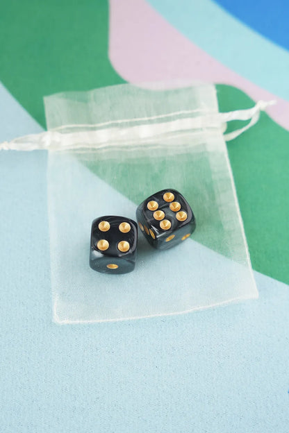 A pair of onyx black 5/8 inch marbled acrylic mahjong dice with gold pips in a sheer organza pouch.