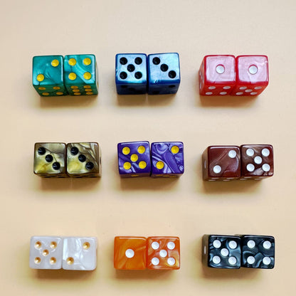 A neat 3x3 grid layout of 5/8 inch marbled acrylic mahjong dice pairs, showcasing unique colorways like jade green with gold pips and royal purple with gold pips on a neutral cream background.