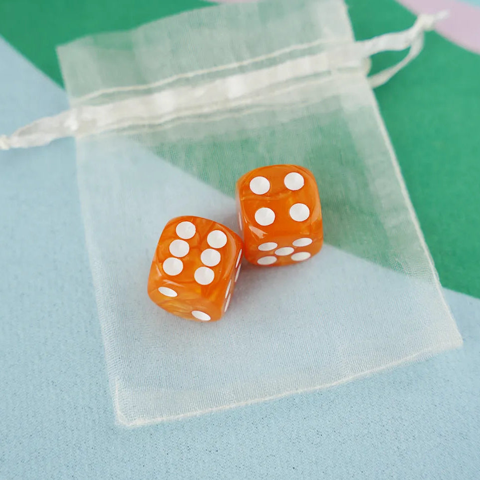 A pair of tangerine orange 5/8 inch marbled acrylic mahjong dice with white pips in a sheer organza pouch.