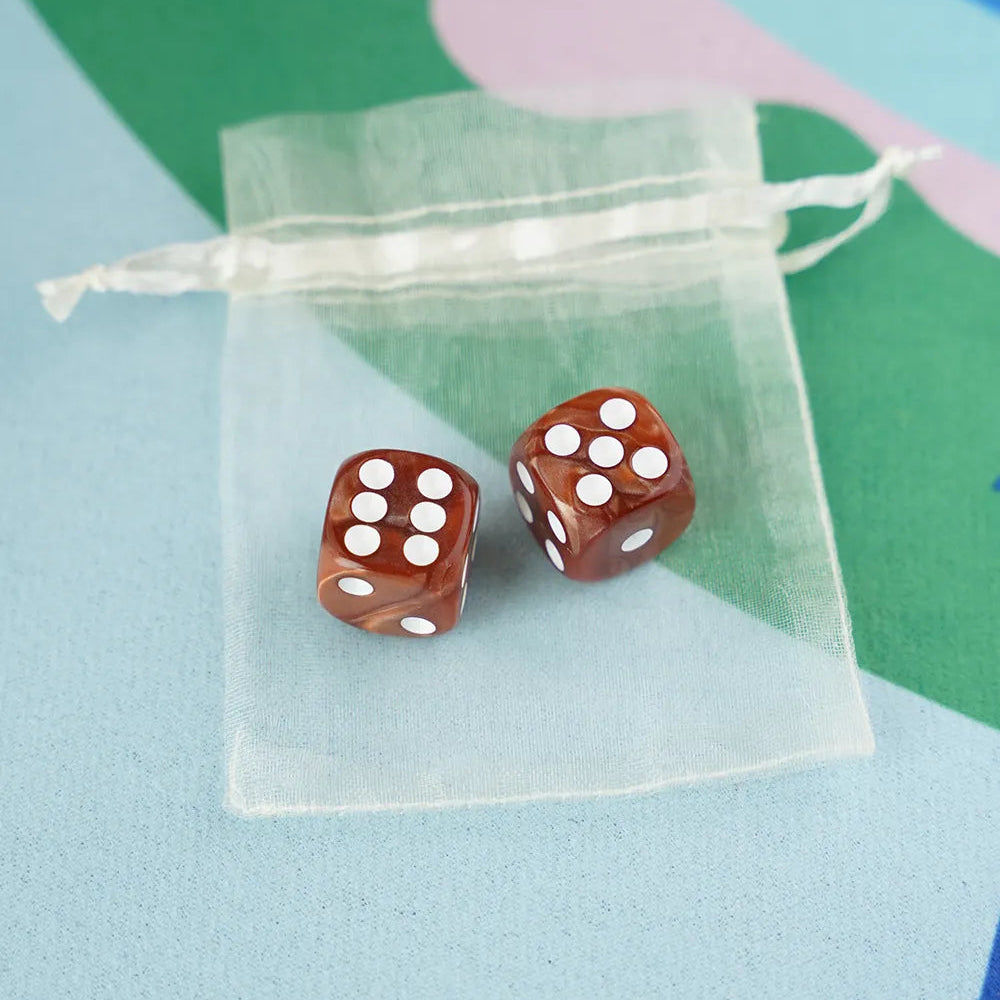 A pair of terracotta brown 5/8 inch marbled acrylic mahjong dice with white pips in a sheer organza pouch.
