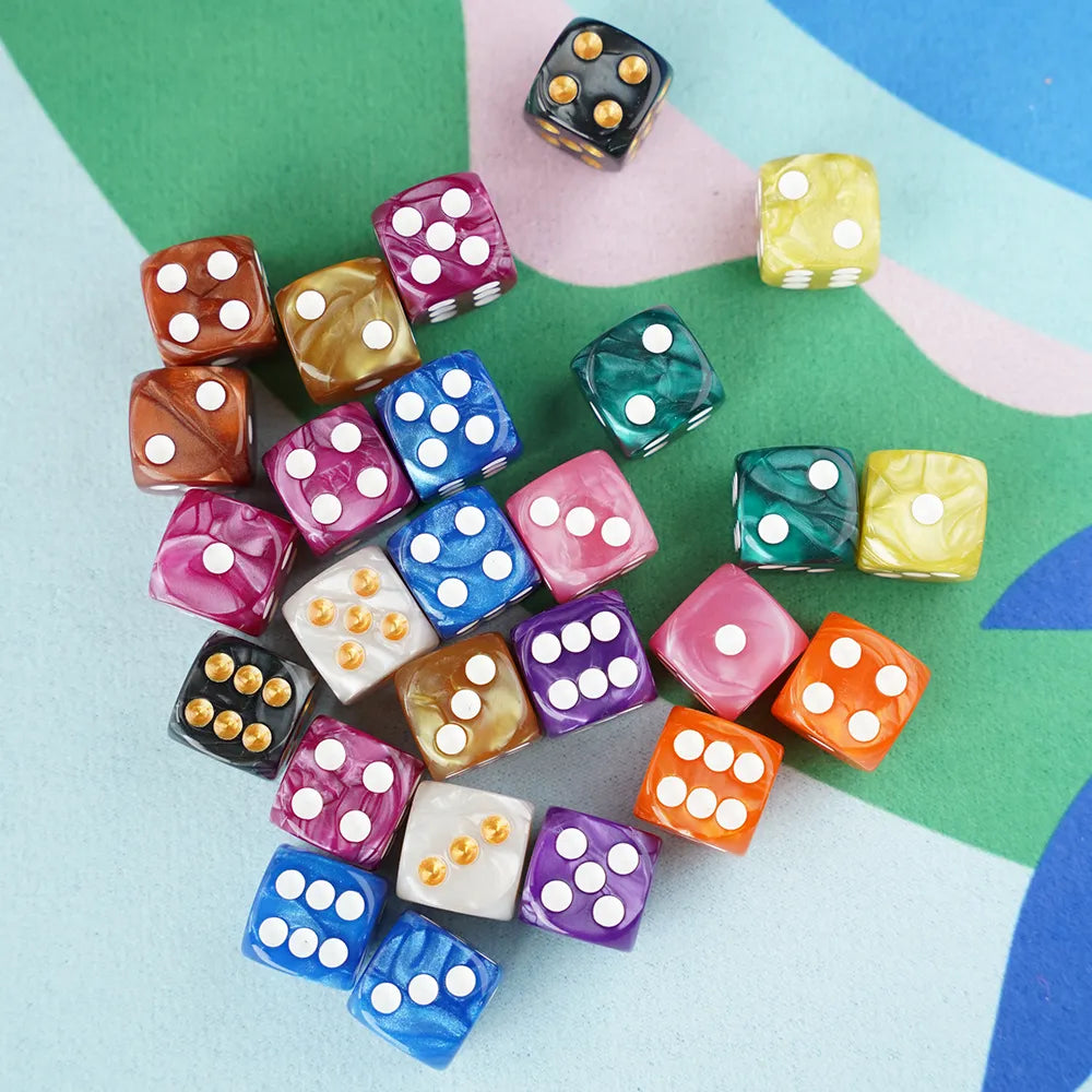 Scattered 5/8 inch marbled acrylic mahjong dice in vibrant jewel tones, displayed on a colorful blue and green color-block playing mat.
